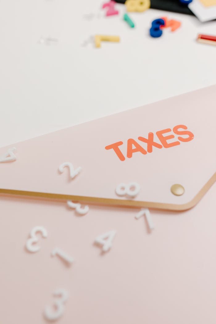 A conceptual image of a pink envelope labeled Taxes with scattered numbers, symbolizing tax calculations.